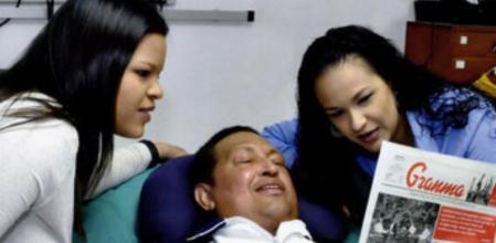 El presidente venezolano Hugo Chávez lee el periódico Granma junto a sus hijas