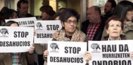 Tres personas muestran pancartas de protesta durante la concentración celebrada esta mañana ante los centros del Gobierno Vasco en Bilbao, por la muerte ayer en la capital vizcaína de José Antonio D.G, que se quitó la vida arrojándose al vacío desde su vivienda cuando una comitiva judicial intentaba acceder a ella para desahuciarle por el impago del alquiler