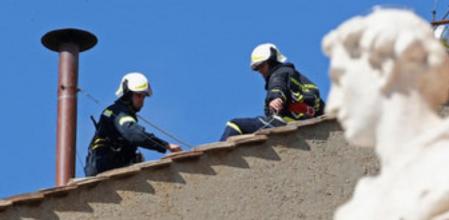 Operarios colocan la chimenea de la que saldrá la 'fumata blanca'