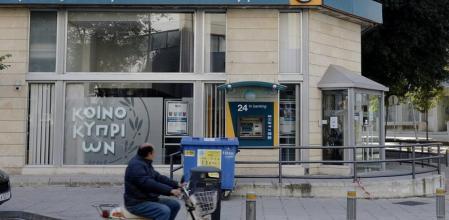 Un hombre circula en motocicleta delante de una sucursal del Banco de Chipre en Nicosia.
