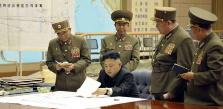 El líder norcoreano, Kim Jong-un (c), durante una reunión en la madrugada de este viernes en un lugar indeterminado, en la que ordenó tener preparados sus misiles para atacar en 