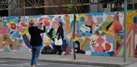 Una turista fotografía el mural recién pintado por el proyecto Efímers de Enrotlla't!, en la esquina de Balmes con Provença