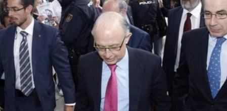 -El ministro de Hacienda, Cristóbal Montoro, pasa junto a un un grupo de afectados por las preferentes que se concentraron a la entrada de la Universidad Internacional Menéndez Pelayo donde hoy se celebró el seminario 'Competitividad y Marca España'.