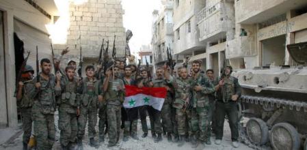 Soldados del ejército sirio sostienen la bandera oficial en el feudo rebelde de Al Jalidiya, en Homs