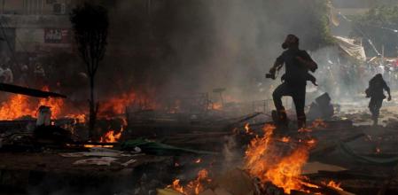 Un fotógrafo huye de las llamas y el gas lacrimógeno durante los disturbios en Egipto