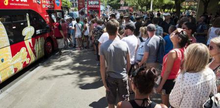 Turistas haciendo cola delante del bus turístico