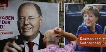 Un hombre que descansa en un banco en Olpe (Alemania)parece dudar ante los carteles electorales de la canciller alemana, Angela Merkel (CDU,) y su principal rival en las elecciones de este domingo, el candidato socialdemódrata Peer Streinbrück