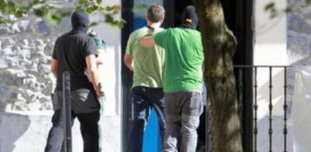 Agentes de la Guardia Civil custodian a uno de los quince integrantes de Herrira, la organización de apoyo a los presos de ETA y sucesora de Gestoras Pro Amnistía, que han sido detenidos hoy en Hernani