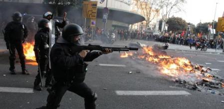 Un mosso antidisturbio lanza un proyectil en una pasada huelga general