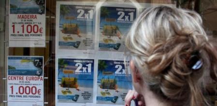 Una mujer consulta el escaparate de ofertas de una agencia de viajes