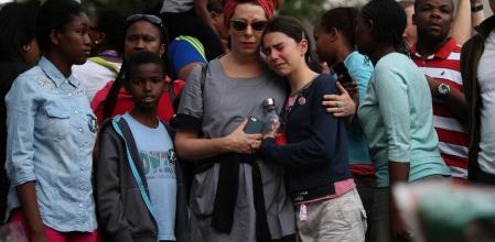Las personas lloran frente un santuario improvisado de flores y velas frente la casa de Nelson Mandela