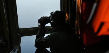 Un miembro de las Fuerzas Aéreas malasias otea con los prismáticos en busca del avión desaparecido.