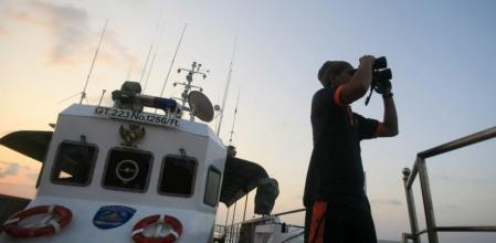 Un miembro del grupo de Búsqueda y Rescate de Indonesia (SAR en sus siglas en inglés) mira a través de unos prismáticos como parte de las actividades de este conjunto para encontrar el avión desaparecido de la aerolínea MalaysianAirlines en aguas pertenecientes al distrito de Sabang, cerca de la frontera con el estrecho de Malacca, en la provincia de Aceh, Sumatra, Indonesia, hoy, viernes 14 de marzo del 2014.