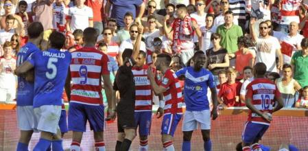 El árbitro muestra tarjeta amarilla al jugador del Granada Fran Rico (c) tras provocar penalti a favor del Almería durante el partido de la trigésima séptima jornada de Liga de Primera División disputado esta tarde en el estadio de Los Cármenes