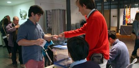 El presidente de una mesa electoral devuelve el DNI a un votante en Terrassa