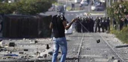 Un joven palestino lanza piedras contra la policía israelí tras la pelgaria del viernes en un suburbio árabe de Jerusalén