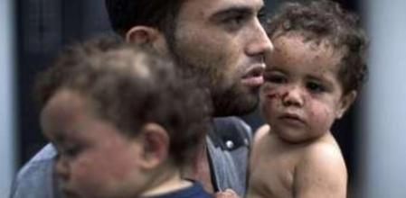 Un hombre carga a sus dos hijas en brazos tras resultar heridas tras el ataque de un tanque en la franja de Gaza