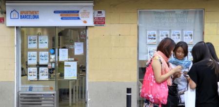 Unas jóvenes charlan frente a una oficina de alquiler de pisos turísticos de La Barceloneta