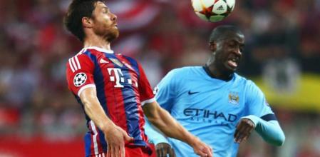 Xabi Alonso disputa un balón a Yaya Touré en el Bayern-City de Champions