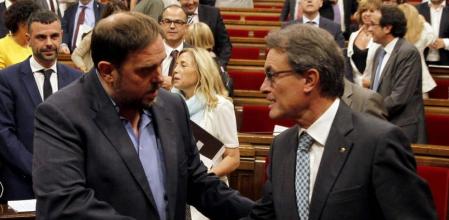 El presidente de la Generalitat, Artur Mas, estrecha la mano del líder de ERC, Oriol Junqueras, después de que el Parlament, en un pleno extraordinario, haya aprobado la Ley catalana de Consultas