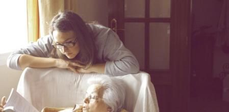 Una anciana y una joven ojean un libro