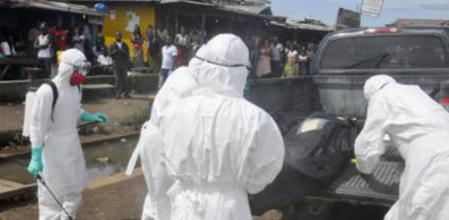 Servicios sanitarios, con uniforme de protección, recepcionan el cadáver de una mujer en Monrovia fallecida presumiblemente a causa del ébola