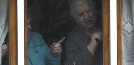 La madre (d) de la auxiliar de enfermería infectada de ébola, Teresa Romero Ramos, mira por la ventana de su vivienda, en Becerreá (Lugo)