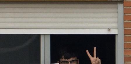 Uno de los 17 aislados en el Carlos II muestra sonriente un cartel que indica su temperatura.