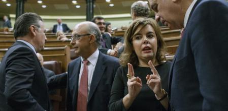 La vicepresidenta Soraya Sáenz de Santamaría habla con el ministro del Interior, Jorge Fernández Díaz, en el Congreso de los Diputados, con el ministro de Hacienda, Cistóbal Montoro en el fondo