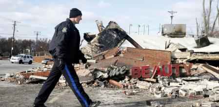 Un policía camina frente a uno de los edificios que ha ardido en los disturbios en Ferguson.