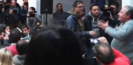 Captura del momento en el que el camarero del 15M, a la derecha, interrumpe el arranque de la conferencia del dirigente de Podemos, Juan Carlos Monedero