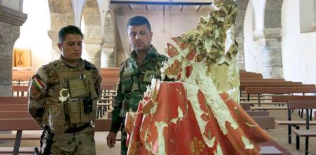 Un peshmerga kurdo y el comandante cristiano Safa Khamro, ante la imagen destruida del Sagrado Corazón en una iglesia de Taleskef