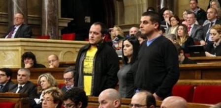 Los tres diputados de la CUP, de pie escuchando la respuesta del conseller de Interior