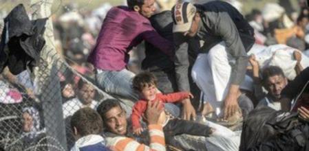 Civiles sirios cruzan por una apertura en la valla fronteriza con Turquía huyendo de los combates entre kurdos y Estado Islámico