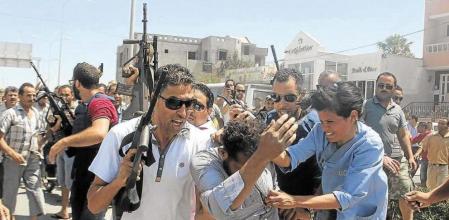 Agentes de policía intentan proteger de la multitud a un detenido, inicialmente considerado sospechoso de participar en la matanza