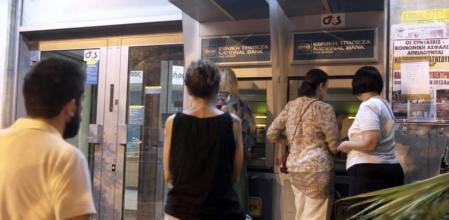 Los clientes esperan para sacar dinero en metálico ante un cajero del Banco Nacional de Grecia