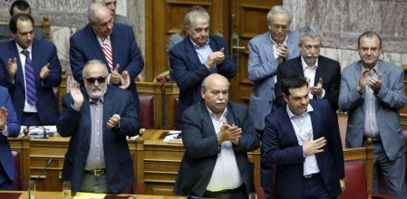 Los ministros del gobierno heleno aplauden al primer ministro Alexis Tsipras tras su discurso a favor de la celebración de un referéndum