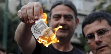 Unos griegos queman un billete de cinco euros en señal de protesta