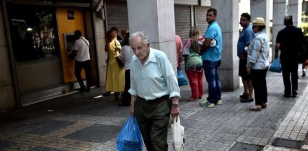 Un hombre mayor camino ante la cola en un cajero en Atenas