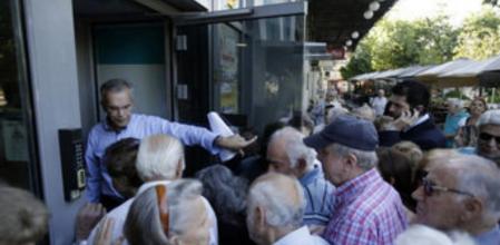 El gerente de un banco griego abre la puerta de la oficina a un grupo de pensionistas en Atenas a principios de julio