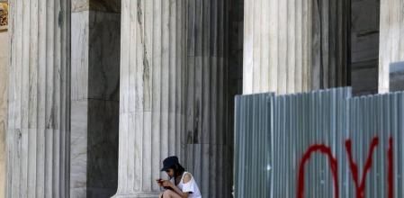Una turista japonesa en la Academia de Atenas, junto a una pintada de no