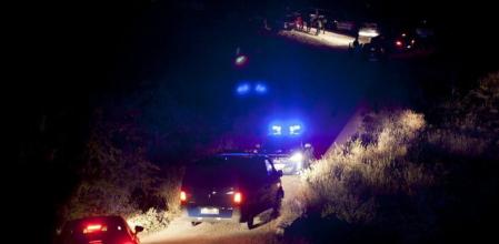 Varios coches de policia en los alrededores de la zona en la que han aparecido los cuerpos.