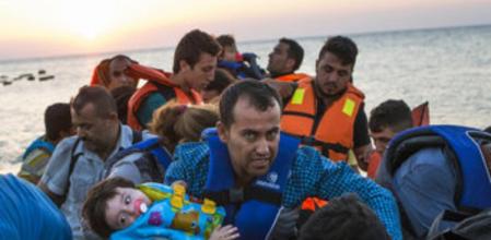 Un hombre carga con una niña al desembarcar de una barca en la isla griega de Kos