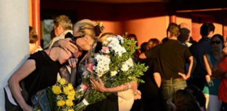 Unas amigas de Marina, con ramos de flores en las manos, no pueden evitar el abrazo emocionado ante el dolor por la pérdida.