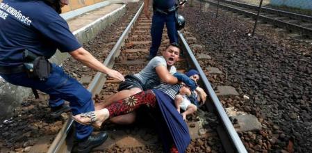 Una pareja de refugiados con un bebé trata de zafarse de la policía en la estación de tren de Bicske