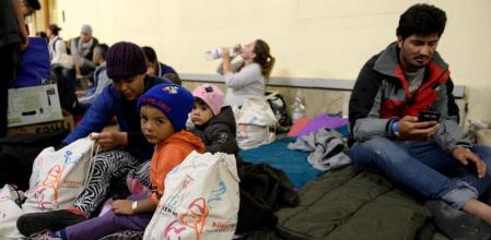 Los primeros refugiados que han llegado en autobús a la frontera austro-húngara esperan en la estación de tren