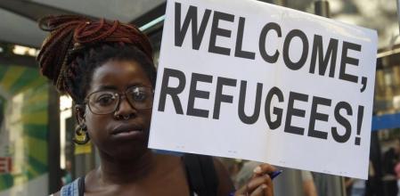 Una mujer lleva una pancarta en la manifestacion a favor de los refugiados en Madrid