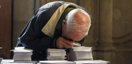 Una persona observa con una lupa las papeletas de los diferentes partidos que concurren a las elecciones al Parlament que se celebran hoy en Catalunya en una jornada en la que un total de 5.314.736 personas están llamadas hoy a votar, a las que se suman los 196.062 residentes en el extranjero