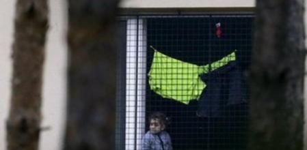 Un niño asomado a una ventana enrejada del centro de detención de extranjeros de Bela Jezova