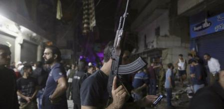 Un hombre armado usa su teléfono en la zona del atentado al sur de Beirut